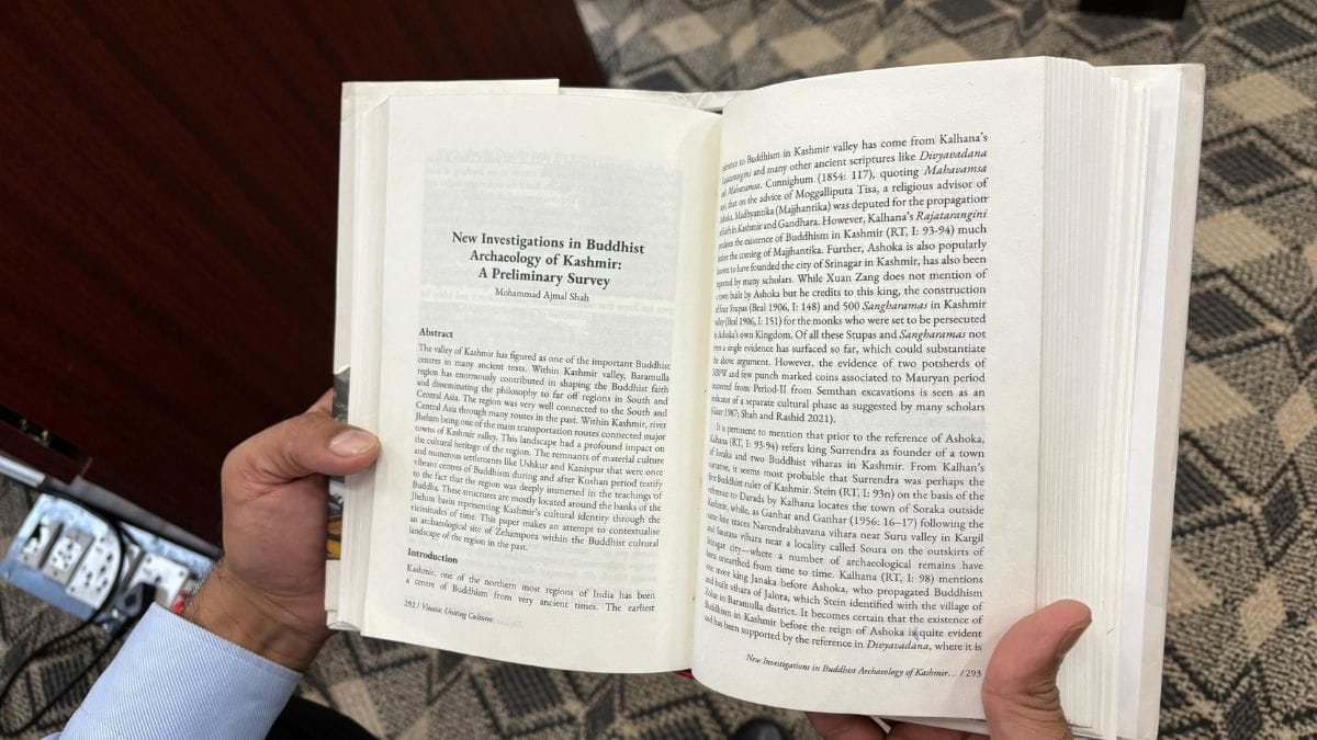 Mohammad Ajmal Shah shows his paper, 'New Investigations in Buddhist Archaeology of Kashmir: A Preliminary Research', which has been published in a book | Photo: Anisha Nehra, ThePrint