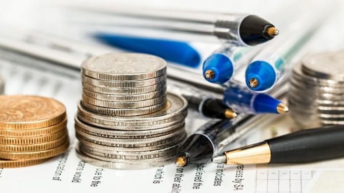 A photo of coins, pens, and a paper, representing economics