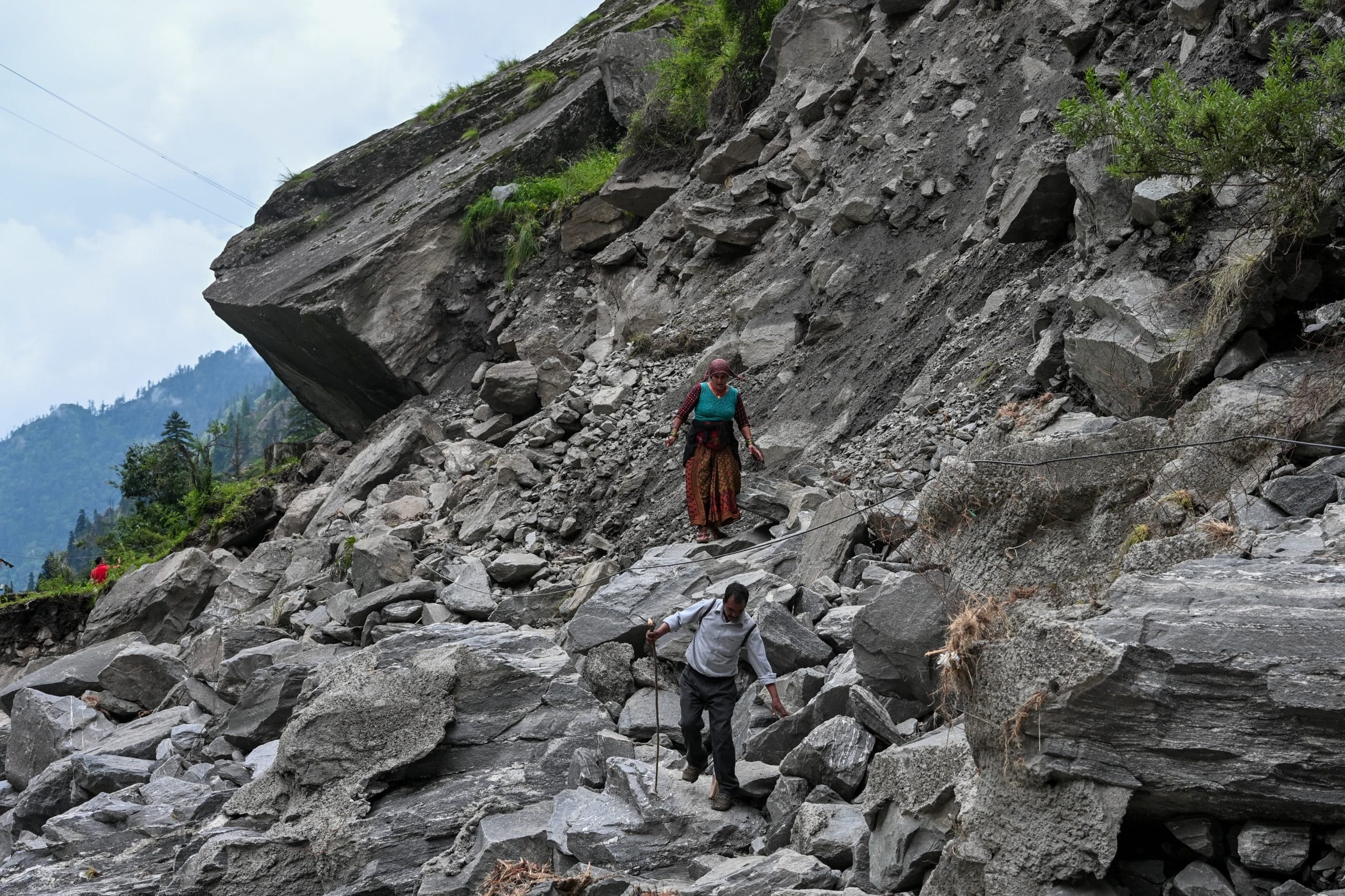 Villagers walk through debris to reach other side of a road which was washed away | Suraj Singh Bisht | ThePrint