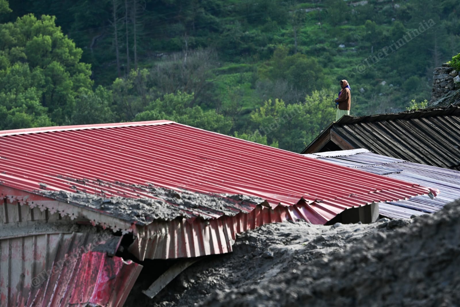 A woman stands on the roof watching the rescue operation in Dharali | Suraj Singh Bisht | ThePrint