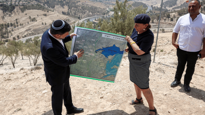 Israeli Finance Minister Bezalel Smotrich and a woman hold a map that shows the long-frozen E1 settlement scheme, that would split East Jerusalem from the occupied West Bank, on the day of a press conference near the Israeli settlement of Maale Adumim, in the Israeli-occupied West Bank, August 14, 2025 | Reuters file photo