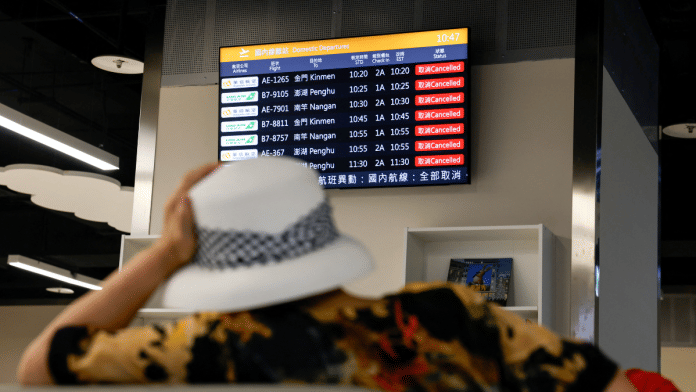 A woman sits in front of a screen displaying information on cancelled domestic flights, as Typhoon Podul approaches the country, in Taipei, Taiwan on 13 August 2025. | Ann Wang | Reuters