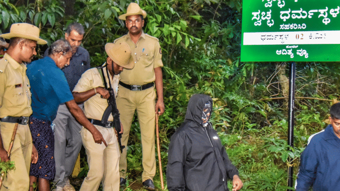 Security personnel with the whistleblower (covered in black) at Dharmasthala in karnataka's Dakshina Kannada district on Monday | PTI