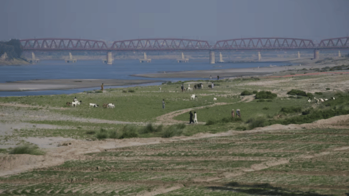 People walk next to a cultivated land on the dry riverbed of the Indus River in Hyderabad, Pakistan April 25, 2025 | Reuters