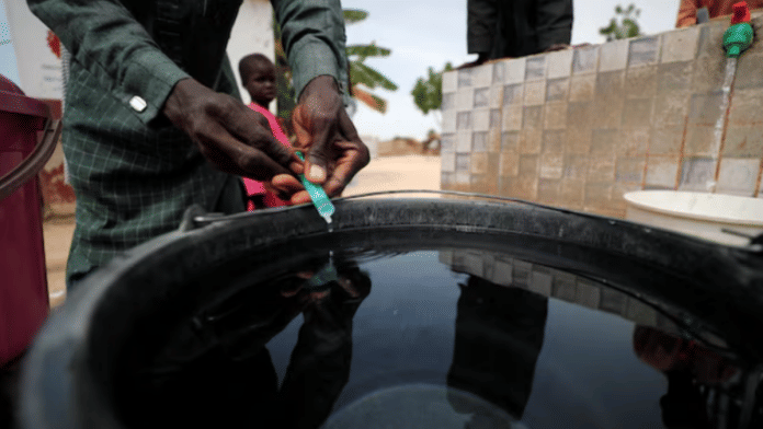 A community health worker adds chlorine to water while internally displaced people gather to fill their buckets at the water point in Muna Garage IDP camp in Maiduguri, Borno State, Nigeria October 23, 2022 | File Photo | Reuters