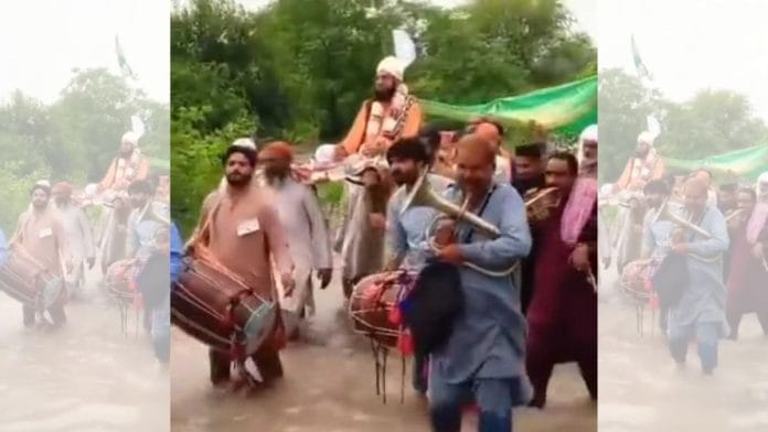 People carrying a pir on a charpoy on a flooded road