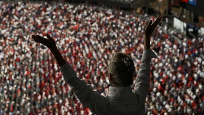 A person raises their arms while attending a memorial service for slain conservative commentator Charlie Kirk at State Farm Stadium, in Glendale, Arizona, on 21 September 2025. | Callaghan O'Hare | Reuters