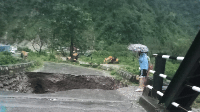 People look at a caved-in portion of a bridge after heavy rains triggered a cloudburst, near Maldevta in Dehradun, on 16 September 2025. | PTI
