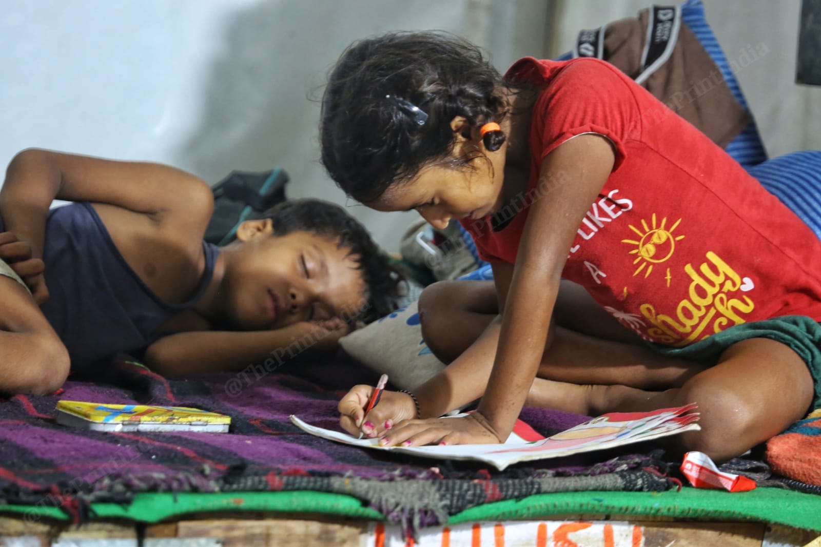 A child studying at a shelter of flood-affected people after their houses were submerged in the floodwater, at Mayur Vihar | Praveen Jain | ThePrint.