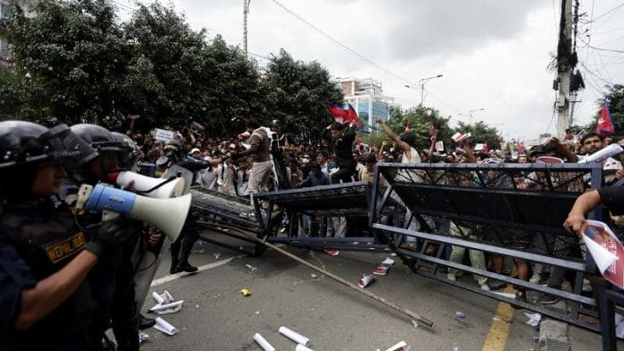Demonstrators run for cover as they are chased away by riot police officers while trying to enter the parliament during a protest against corruption and the government's decision to block several social media platforms, in Kathmandu, Nepal, September 8, 2025.