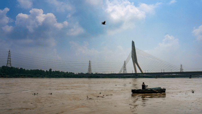 A man rows his boat across the swollen Yamuna river during the monsoon season, near Signature Bridge, Wazirabad in New Delhi on 30 August 2025 | PTI