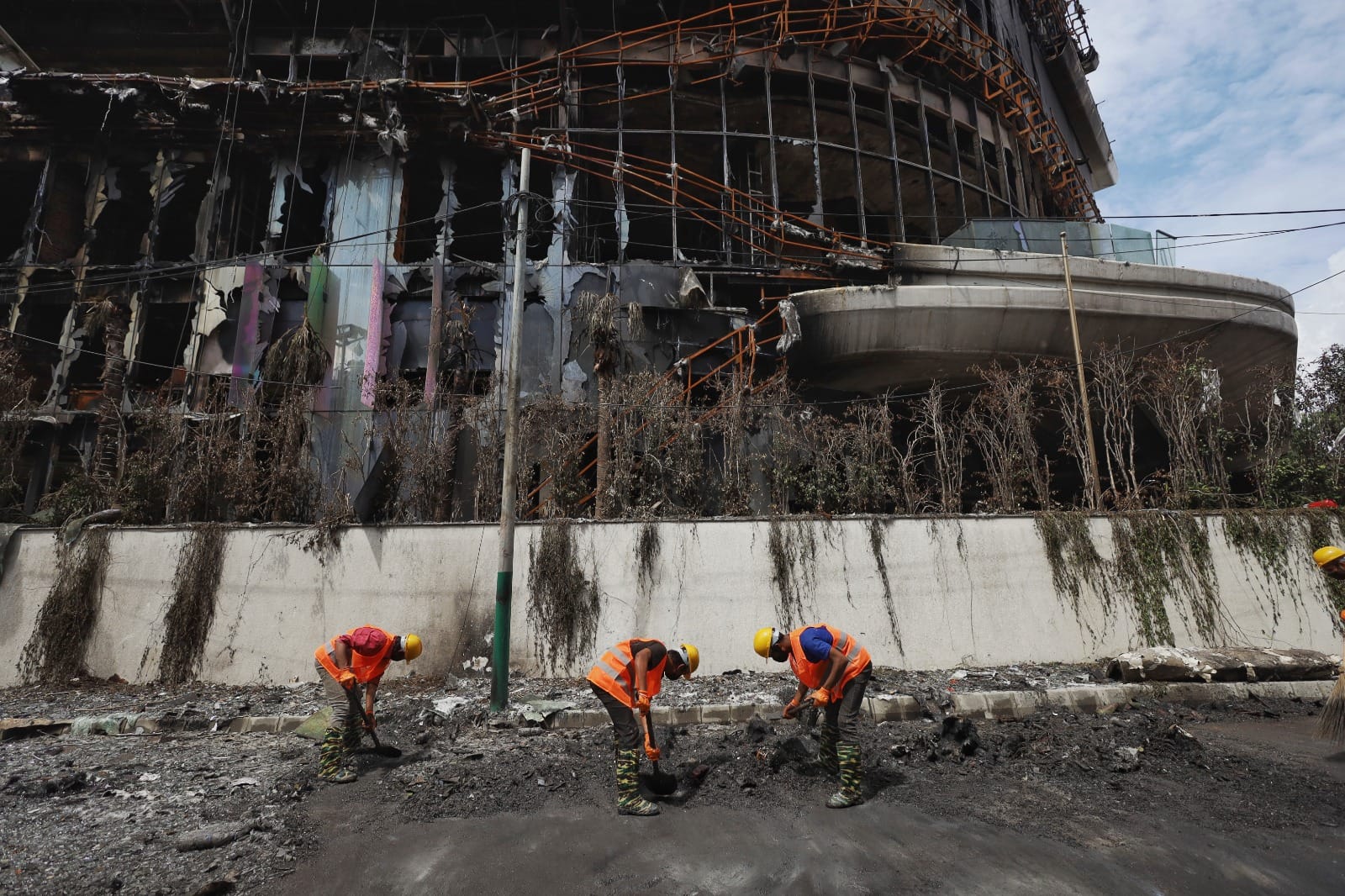 Workers clean debris lying on the road outside Hilton Kathmandu | Manisha Mondal | ThePrint