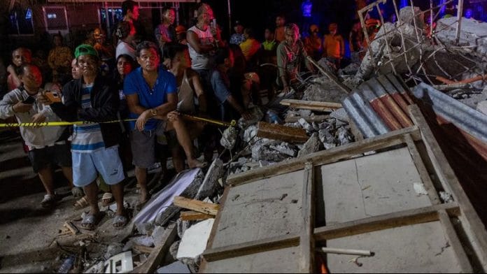 Residents watch as rescuers retrieve bodies of victims found under the rubble of a damaged pension house in the aftermath of a magnitude 6.9 quake in Bogo, Cebu on 1 October 2025. | Eloisa Lopez | Reuters