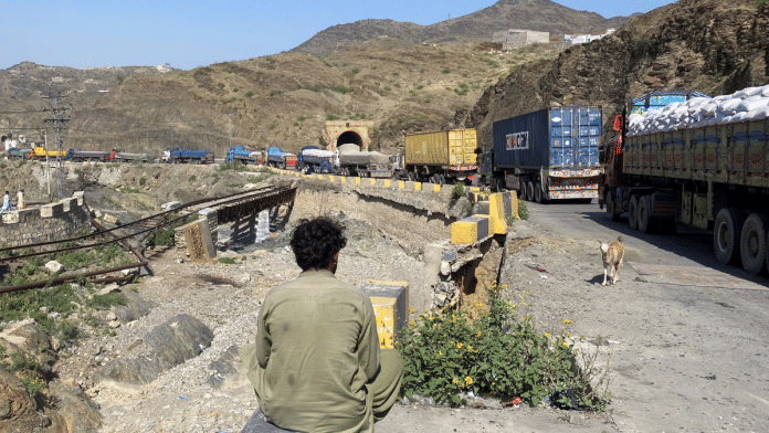 A man sits next to trucks parked at the Torkham border crossing, after Pakistan closed border crossings with Afghanistan, following exchanges of fire between the forces of the two countries, in Torkham on 12 October 2025. | Shahid Shinwari | Reuters