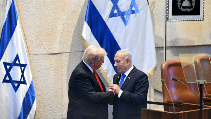 US President Donald Trump (L) holds hands and speaks with Israeli Prime Minister Benjamin Netanyahu at the Knesset, in Jerusalem on 13 October 2025. | Saul Loeb | Pool via Reuters