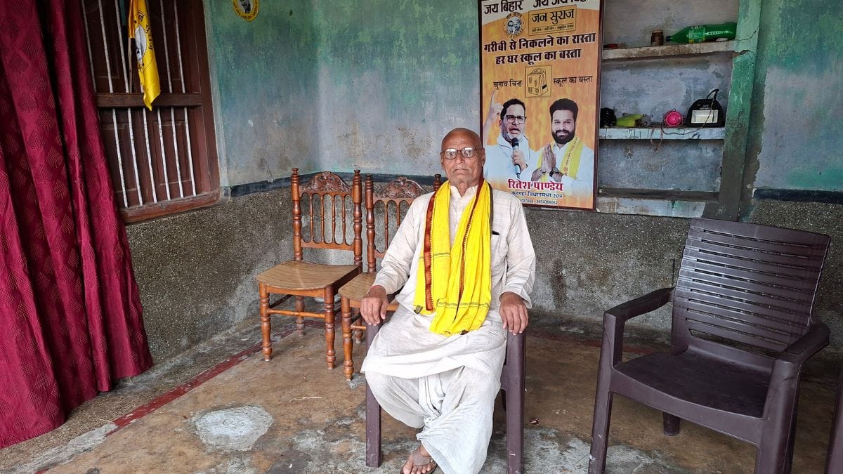 Kedar Pandey, groundskeeper of Kishor's ancestral house in Konar; behind him is a poster of the Jan Suraaj candidate | ThePrint/Prashant Srivastava
