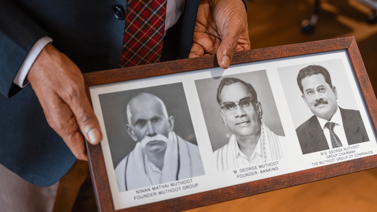 George Alexander Muthoot shows photos of Ninan Mathai Muthoot, founder, left, M. George Muthoot, founder of banking, center, and M.G. George Muthoot, group chairman at the company's headquarters in Kochi, in October | Sameer Raichur/Bloomberg