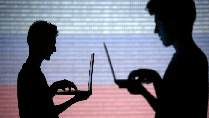 People are silhouetted as they pose with laptops in front of a screen projected with binary code and a Russian national flag, in this picture illustration taken in Zenica October 29, 2014 | Reuters