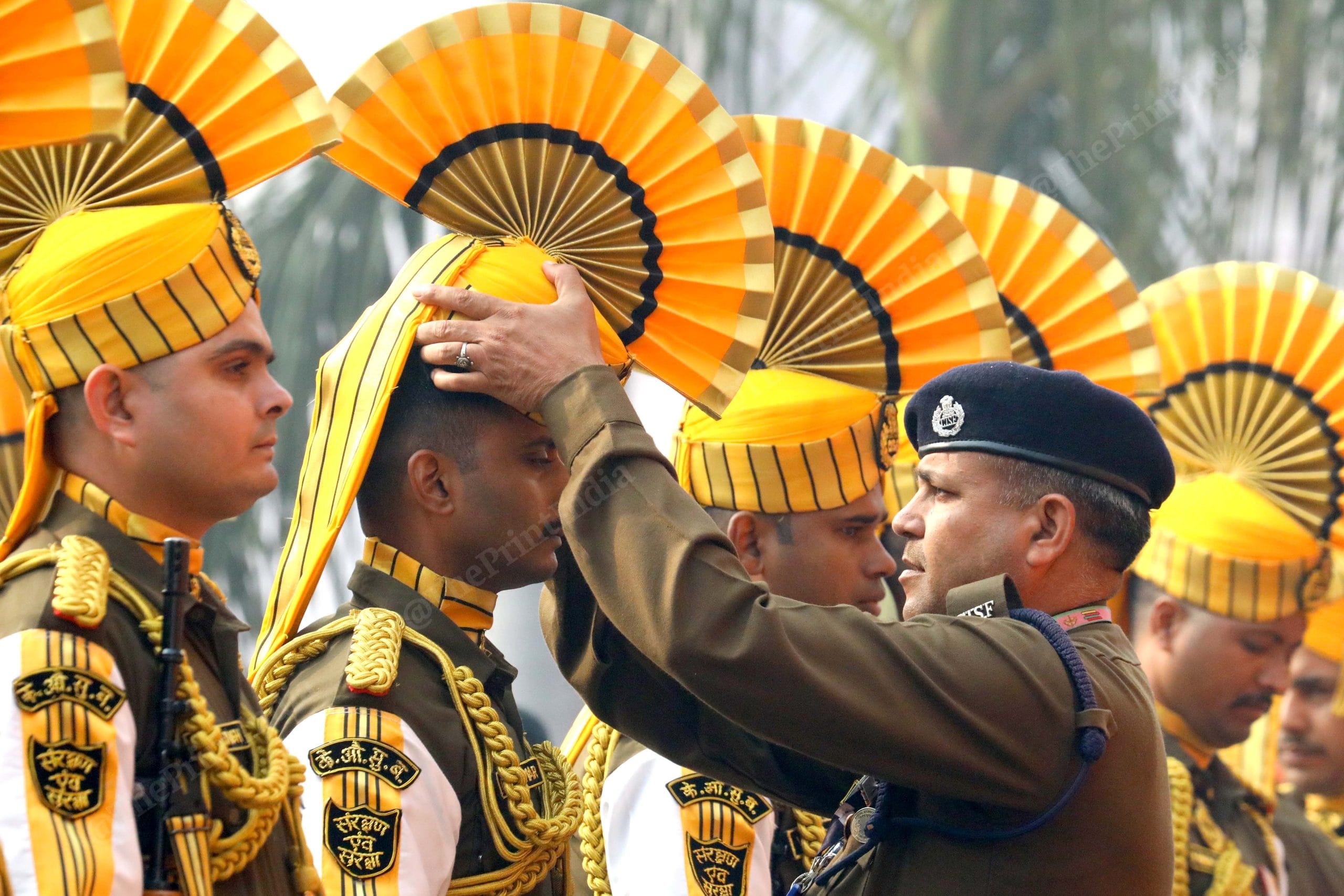 A CISF personnel helps to put on a cap at the Old Parliament building | Praveen Jain | ThePrint