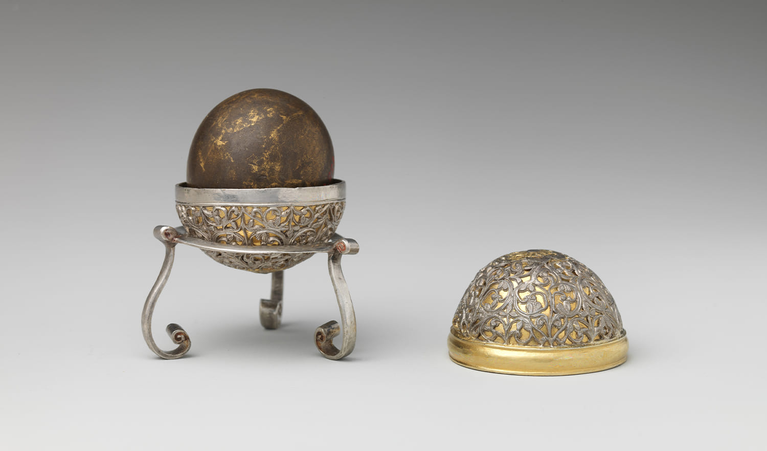 A Goa stone with a spherical silver case and a simpler silver stand.