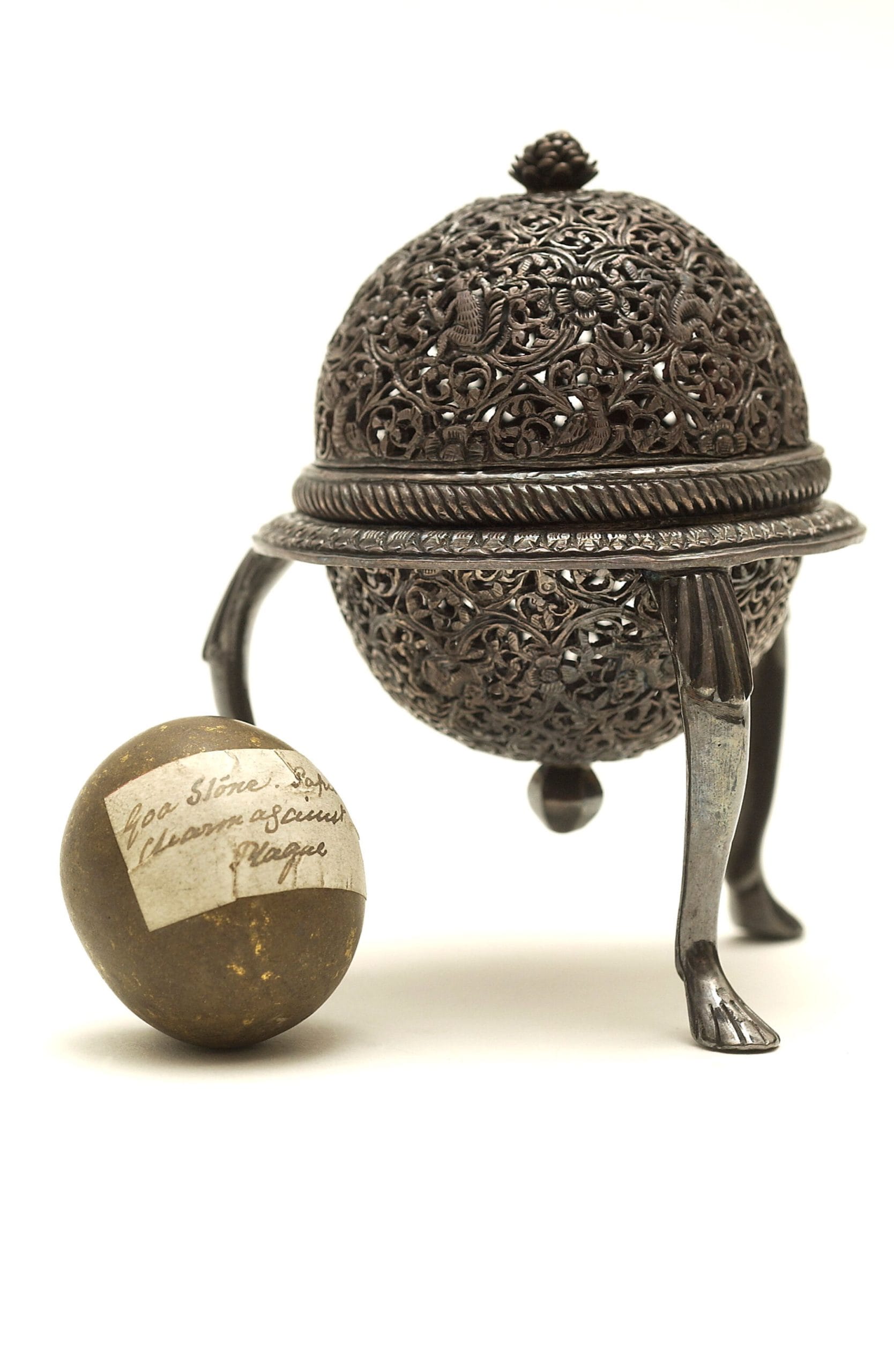 Goa stone beside a slightly oxidised silver case. The case has a floral latticework design.