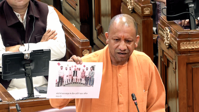 During his speech in assembly, Yogi Adityanath presents photograph which he claimed shows Akhilesh Yadav with those accused of illegal cough syrup trade. | ANI