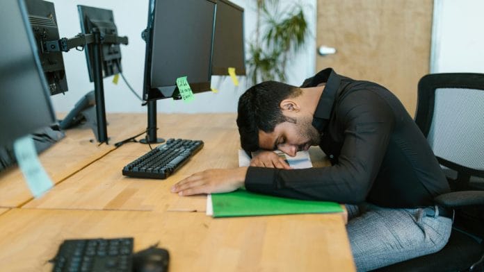 A man leaning on his desk, representing burnout