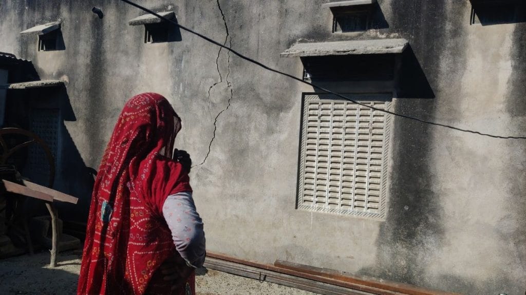 एक महिला पिछले रात के खनन धमाके से टूटे दीवार का निरीक्षण करती हुईं | फोटो: मोहम्मद हम्मद/दिप्रिंट