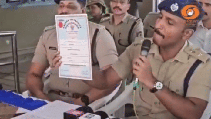 Screengrab showing a police officer displaying fake certificates to the press | X