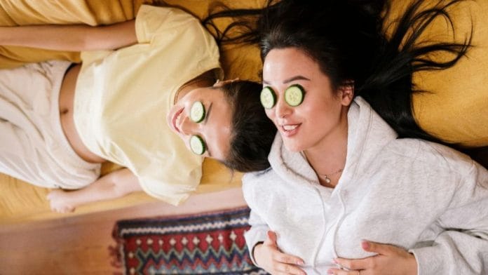 A photo of two women lying down with cucumber slices on their eyes.
