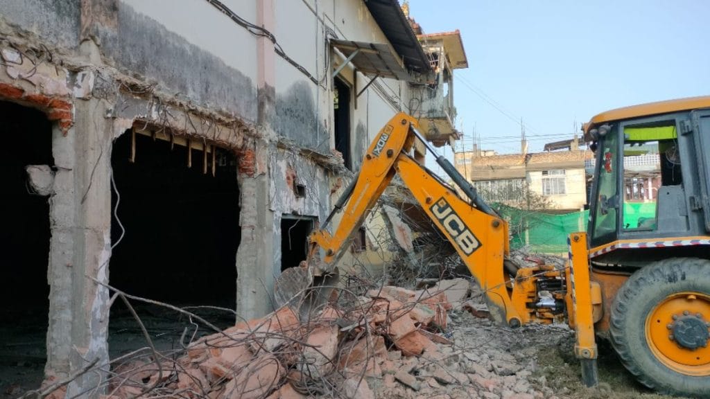 A backhoe loader demolishing the hall. Photo: Kalpajyoti Bhuyan