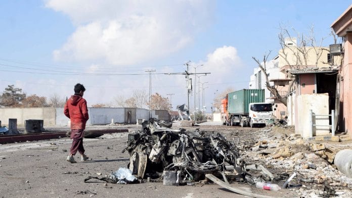 A person walks past the remains of a damaged vehicle at a site, after militant attacks, in Quetta, Pakistan, February 1, 2026. | REUTERS/Stringer