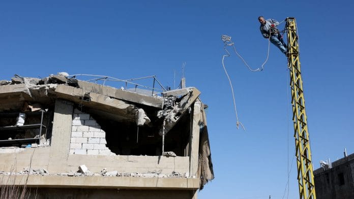 A man works on an electric pole next to a damaged building, in the aftermath of an Israeli strike on friday, in Tamnine el Tahta, Bekaa valley, Lebanon, February 21, 2026. | REUTERS/Mohamed Azakir
