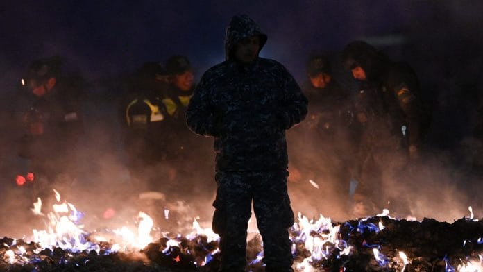 Members of the Bolivian military burn banknotes that fell from a Bolivian Air Force Hercules aircraft after it crashed on Friday evening onto a busy avenue amid inclement weather in the city of El Alto, Bolivia, February 28, 2026. REUTERS/Claudia Morales