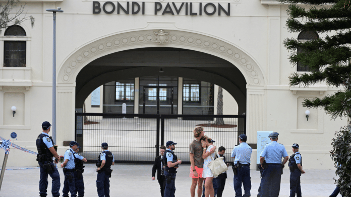 Two people embrace as police officers stand guard outside Bondi Pavilion following the attack on a Jewish holiday celebration at Sydney's Bondi Beach, in Sydney, Australia, December 15, 2025 | Reuters