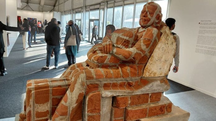 One sculpture, called In Transit, shows a bearded man reclining on a pile of bricks embracing his backpack, with a suitcase locked between his legs. | Rama Lakshmi | ThePrint