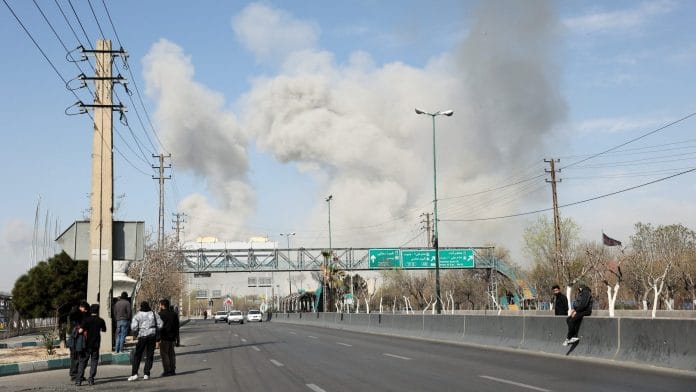 People gather on the sides of a road as smoke rises in the background following an explosion, amid the U.S.-Israeli conflict with Iran, in Tehran, Iran, March 5, 2026. Majid Asgaripour/WANA (West Asia News Agency) via REUTERS