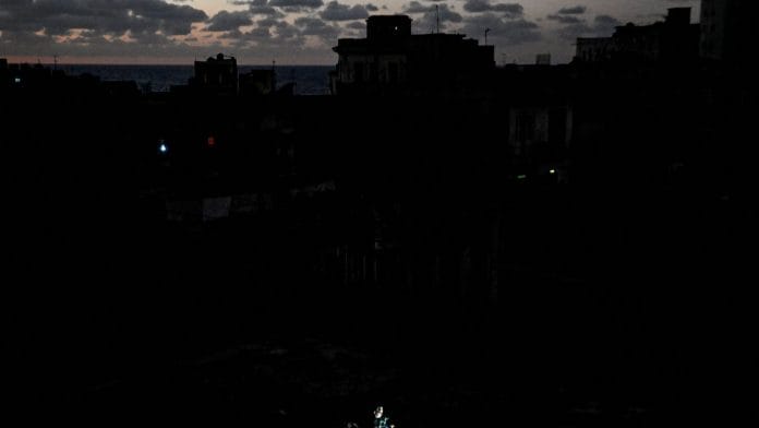 People use their mobile phones while sitting on a roof as Cuba's national electric grid collapsed for the second time in a week amid the U.S.-imposed oil blockade, according to officials, as the communist government struggles to keep the lights on for about 10 million people with decrepit infrastructure, in Havana, Cuba, March 21, 2026. | REUTERS/Norlys Perez