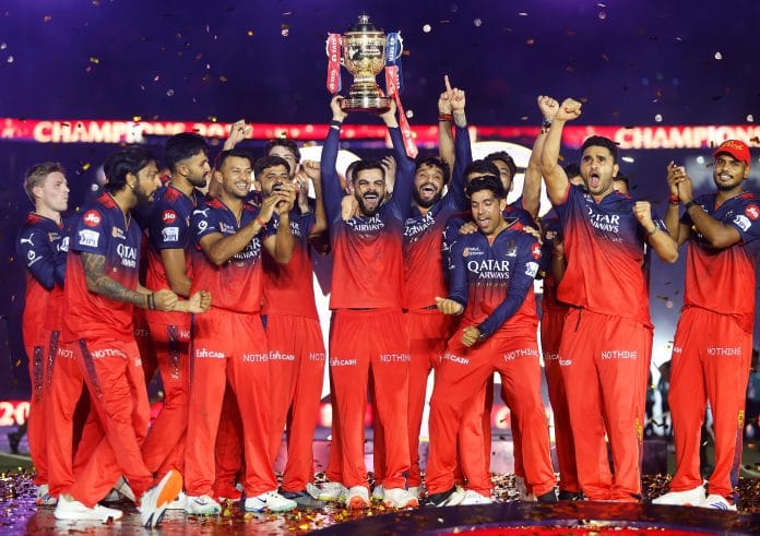 Virat Kohli of Royal Challengers Bengaluru lifts the IPL trophy alongside teammates following the team's victory in the 2025 IPL Final match at Narendra Modi Stadium in Ahmedabad, India on June 3. | Bloomberg