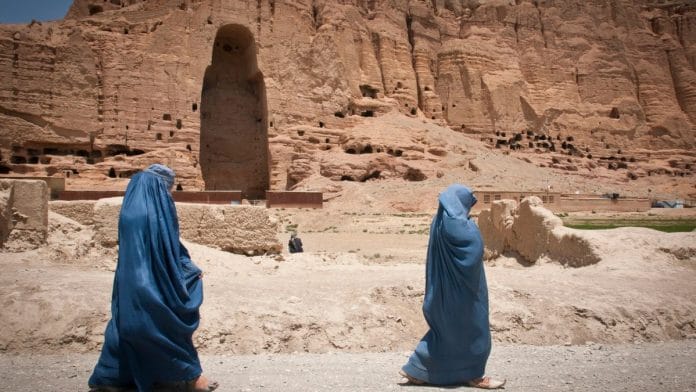 Two women walk past the huge cavity where one of the ancient Buddhas of Bamiyan, known to locals as the 