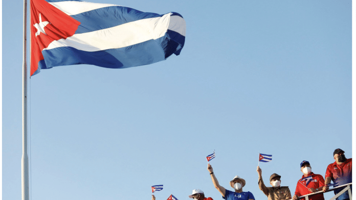 Cuba's President Miguel Diaz-Canel and former President Raul Castro wave national flags as thousands march to Revolution Square to mark May Day, in Havana, Cuba May 1, 2022. | REUTERS/Claudia Daut
