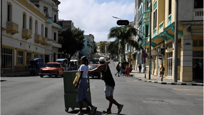 ] People cross an avenue as traffic lights are off during a mass blackout across most of the country, in Havana, Cuba March 4, 2026. | REUTERS/Norlys Perez