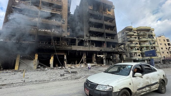 A car drives past burned buildings after an Israeli strike on Beirut's southern suburbs, Lebanon, 7 March, 2026 | Picture taken with a mobile phone | REUTERS/Stringer