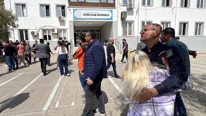 People wait in front of the school building after a deadly shooting, in the southeastern province of Kahramanmaras, Turkey, April 15, 2026. Picture taken with a mobile phone. | IHA (Ihlas News Agency) via REUTERS