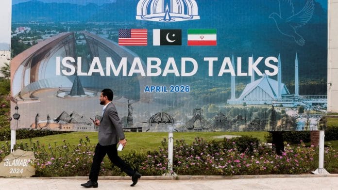 A man walks past a billboard near the media centre in Islamabad on 11 April 2026 | Asim Hafeez/Reuters