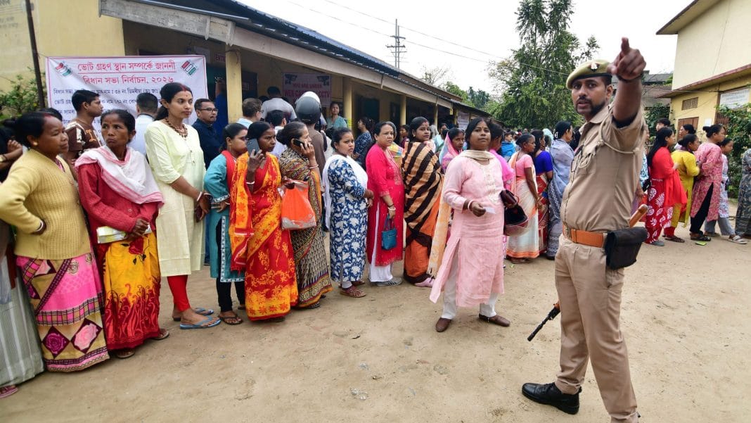 A police official assists people waiting in a queue to cast votes during the Assam Assembly elections, at a polling station at Bonda, in Guwahati, Thursday, April 9, 2026. | PTI Photo