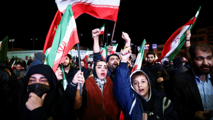 People wave flags as they gather after a two-week ceasefire in the Iran war was announced, in Tehran | Majid Asgaripour/WANA via REUTERS