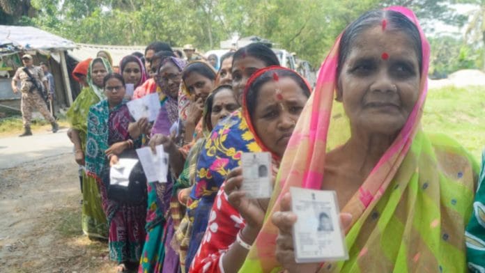 Voters show their voting cards while waiting in line to cast their votes during the first phase of the West Bengal Assembly elections 2026 at a polling station, in Purba Medinipur on Thursday. (ANI Photo)
