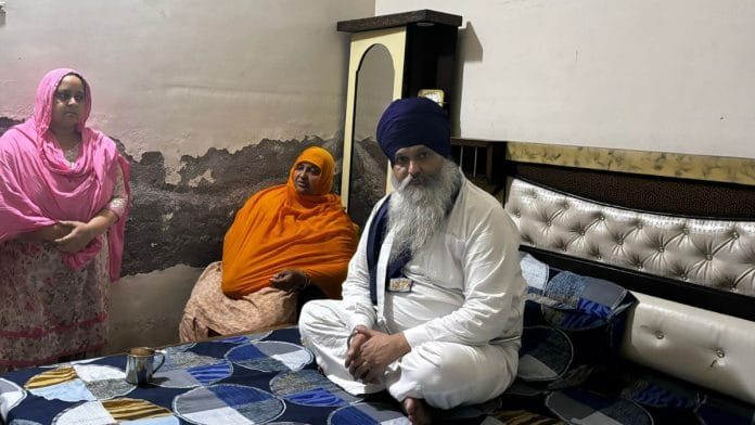 Gurjeet Singh Khalsa sits on his bed as his family and visitors gather around him