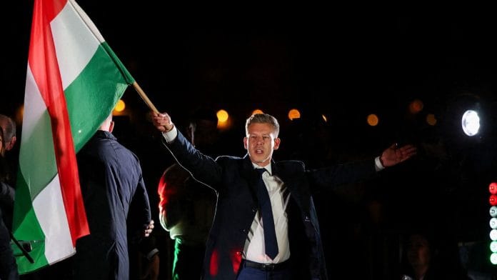 Peter Magyar, leader of Tisza party, waves a Hungarian flag as he celebrates, after Prime Minister Viktor Orban conceded defeat in the parliamentary election in Budapest on 12 April, 2026 | REUTERS/Leonhard Foeger